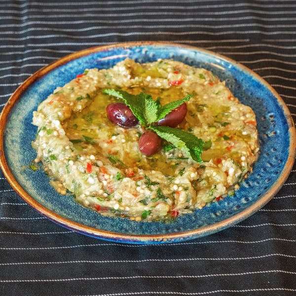 Moustache Pitza's baba ghanoush, garnished with olives and mint, drizzled with olive oil.